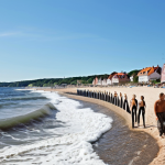 **

"A picturesque coastal town in Skåne, Sweden. Focus on innovative wave breakers protecting the beach, while creating a recreational space. Summer setting, clear skies, happy people enjoying the beach and the new wave breakers."

**